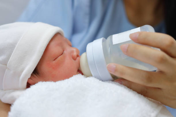 bebê recém-nascido pequeno que suga o leite no frasco - sucking asian ethnicity baby mother - fotografias e filmes do acervo