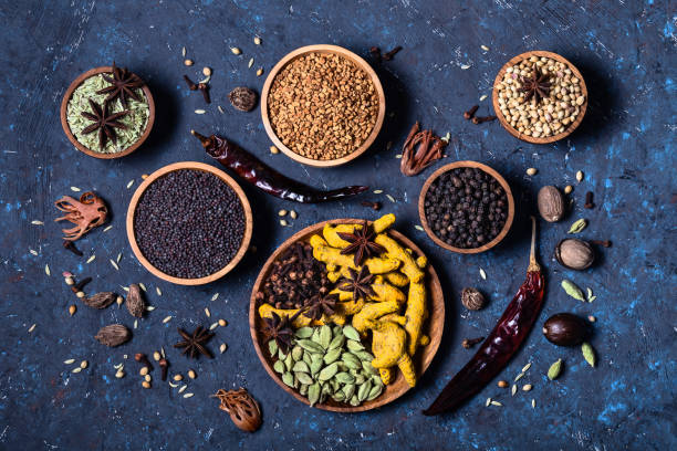 Dry whole Indian spices in wooden bowls on dark blue concrete rustic background. Dry whole warming Indian spices in wooden bowls on dark blue concrete background. Exotic vitamin, flavor, alternative medicine, seasoning, Ayurvedic. Turmeric, clove, cardamom, pepper, anise, fennel. ayurveda cardamom star anise spice stock pictures, royalty-free photos & images