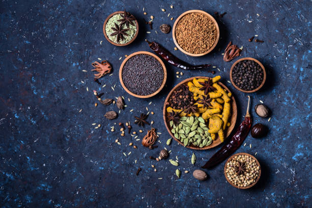 Dry whole Indian spices in wooden bowls on dark blue concrete rustic background. Dry whole warming Indian spices in wooden bowls on dark blue concrete background. Exotic vitamin, flavor, alternative medicine, seasoning, Ayurvedic. Turmeric, clove, cardamom, pepper, anise, fennel. ayurveda cardamom star anise spice stock pictures, royalty-free photos & images