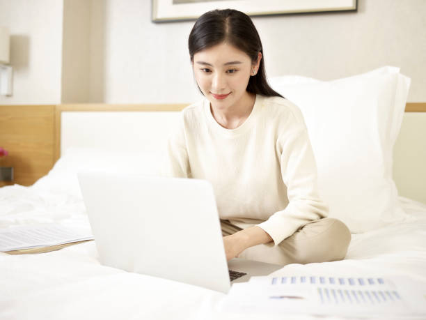 istock young asian woman using laptop on bed 1188333720
