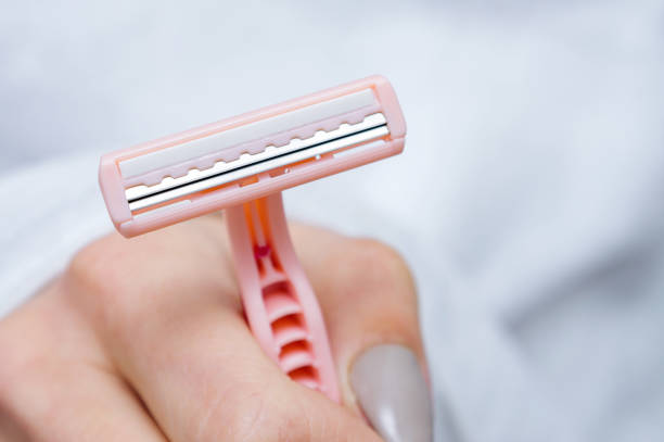 A lady's shaver in female hand. Close-up, selective focus. A lady's shaver in female hand. Close-up, selective focus. body hair stock pictures, royalty-free photos & images