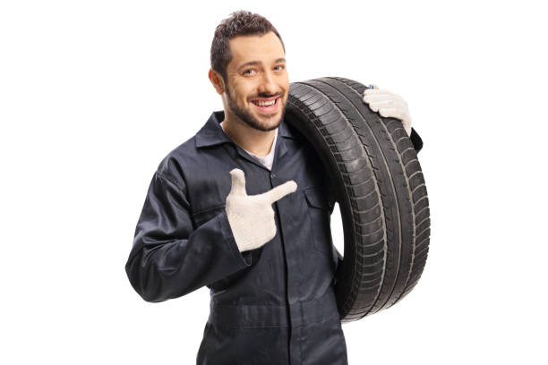 istock Car mechanic carrying a tire and pointing 1188342709