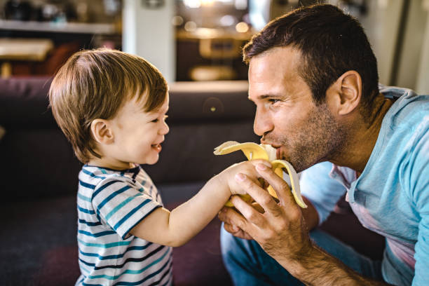 istock Small happy boy feeding his single father with banana. 1188349025