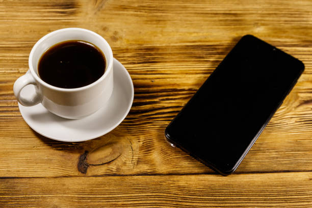istock Cup of coffee and smartphone on a wooden table 1188349463