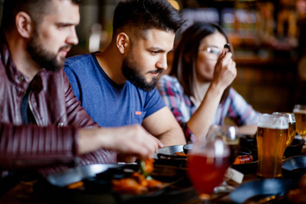 istock Young man with friends at the table in a pub 1188354455