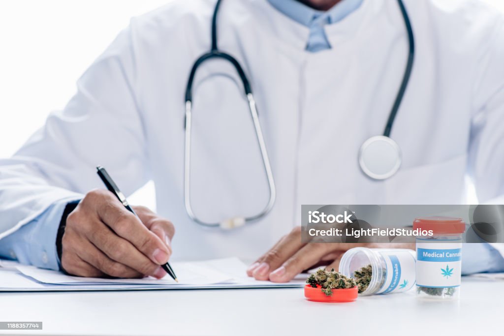 cropped view of doctor in white coat writing isolated on white Medical Cannabis Stock Photo