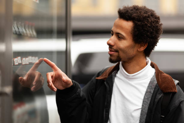African man buys drink or sweets at vending machine outside African man buys drink or sweets at vending machine outside. man hand holding candy bar stock pictures, royalty-free photos & images