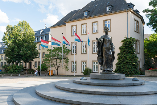 Luxembourg City / Luxembourg - 10. August, 2019:  the Place Clairefontaine with flags of Luxembourg and statue of Grand Duchess Charlotte of Luxembourg