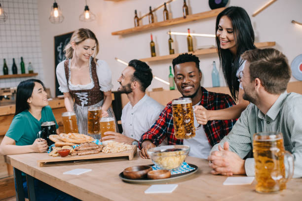 istock two attractive waitresses serving beer for multicultural friends in pub 1188363172