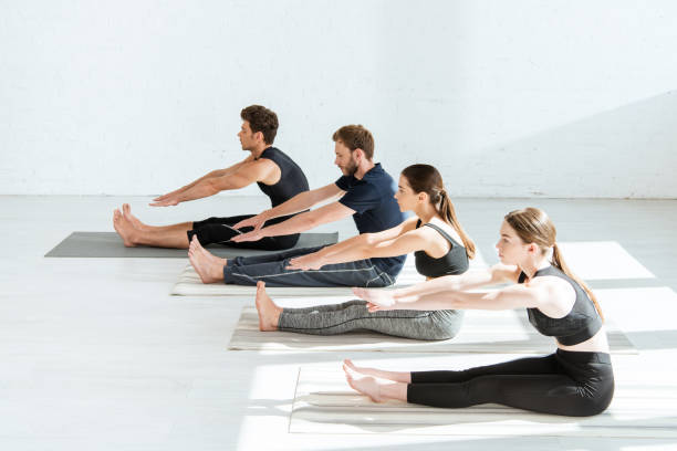 istock young people in sportswear practicing yoga in seated forward bend pose 1188363320