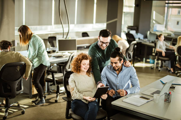istock Happy colleagues using touchpad at full corporate office. 1188363498