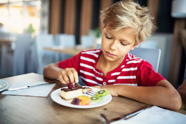 istock Little boy eating cheesecake and fresh fruit 1188363575