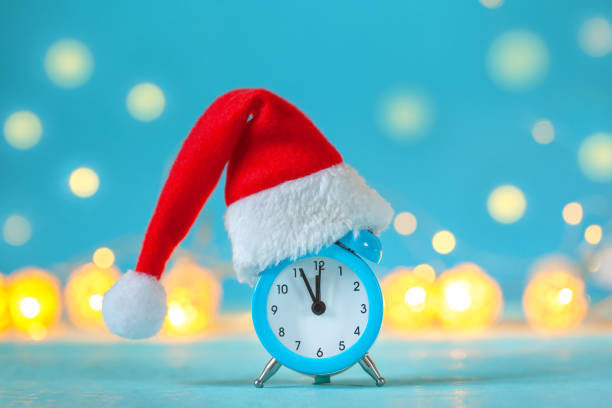 istock Alarm clock with Christmas Santa hat on blue background. Time for Christmas. 1188366484