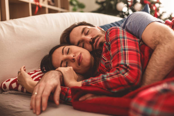 felice coppia eterosessuale che dorme insieme a letto abbracciata - spooning love embracing men foto e immagini stock