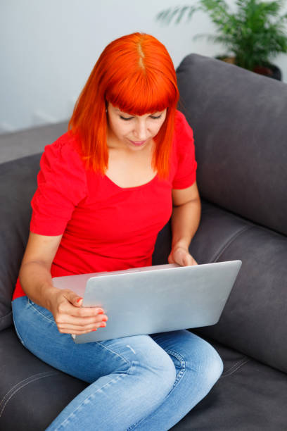 istock Redhead woman with a laptop at home 1188368016