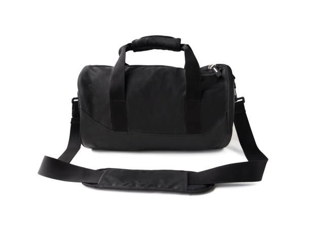 Black duffel bag with handles and shoulder strap isolated Black duffel bag with handles and shoulder strap. Sports equipment for gym isolated on white background luggage strap stock pictures, royalty-free photos & images