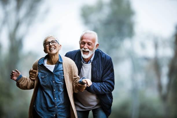 公園で楽しんでいる遊び心のあるシニアカップル。 - senior adult fun autumn senior couple ストックフォトと画像