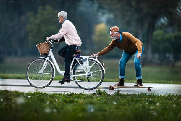 istock Happy senior woman cycling and pulling her husband on a skateboard. 1188370362