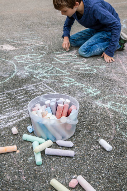 istock Young boy drawing on the sidewalk with chalk 1188371235