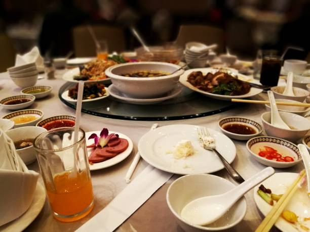 leftover food on a table after a big party. wasteful spending and lifestyle. food waste contribution to global warming problem situation. leftover Chinese food on round table.
