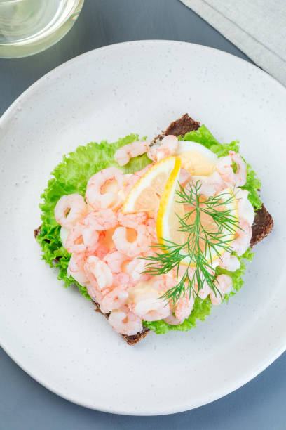 istock Traditional savory swedish sandwich with a dark bread, lettuce, eggs, mayonnaise, shrimps, dill and lemon, vertical,  top view 1188373355