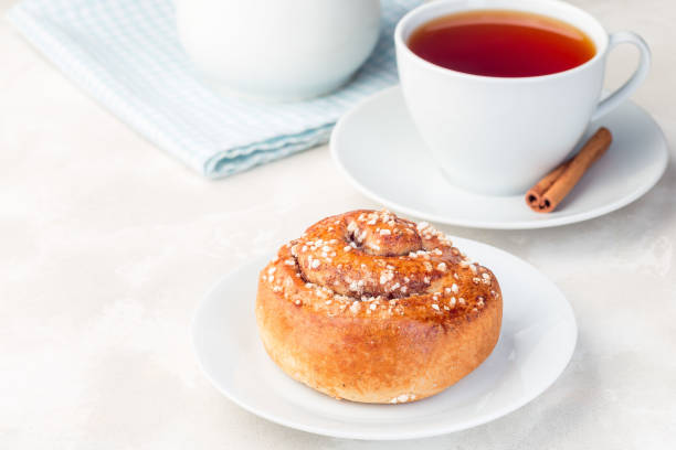 istock One cinnamon bun on a white plate, served with a cup of red tea, horizontal, copy space 1188374006