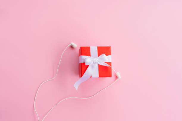 istock red gift box with white ribbon and headphones on pink background 1188376885