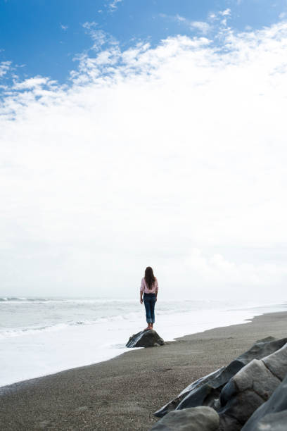 istock Rear view of a woman walking along an empty beach 1188377095