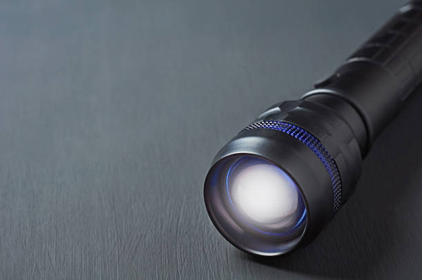 One black tactical flashlight lies on dark concrete table. Space for text