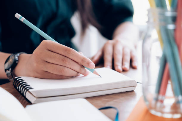 istock Close up female hands with pen writing on notebook. 1188381458