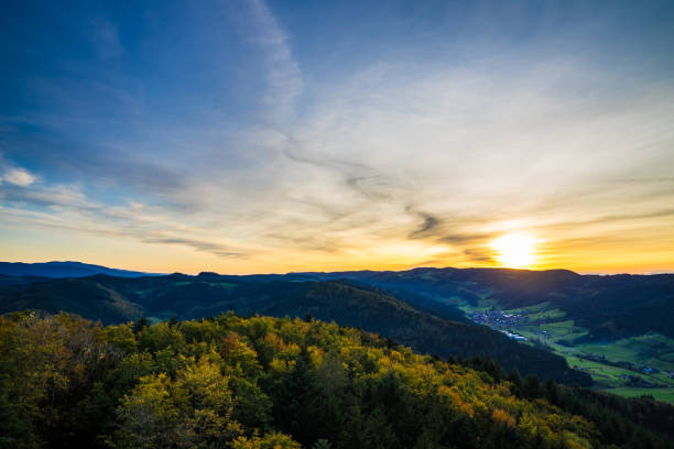 Germany, Endless view over beautiful untouched natural black forest nature landscape above tree tops in warm orange sunset light in autumn season