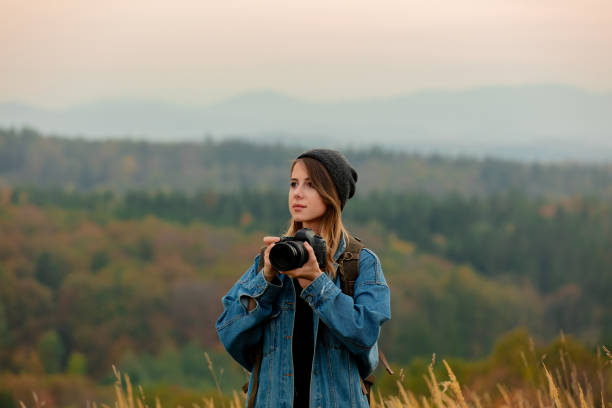 istock Style girl with camera and backpack at countryside with mountains on background 1188382898