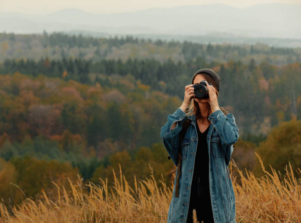 istock Style girl with camera and backpack at countryside with mountains on background 1188382905