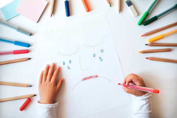 niño dibujando cara triste en el papel. - child drawing fotografías e imágenes de stock