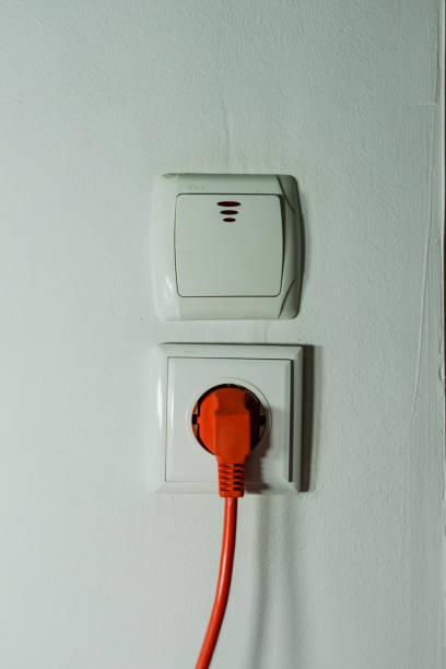 spina elettrica, presa elettrica e accensione di una parete bianca. - electric plug outlet human hand electricity foto e immagini stock
