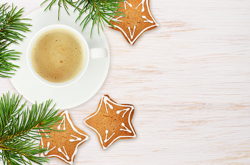 Ginger cookies and cup of coffee with twigs of Christmass tree on white painted wooden background