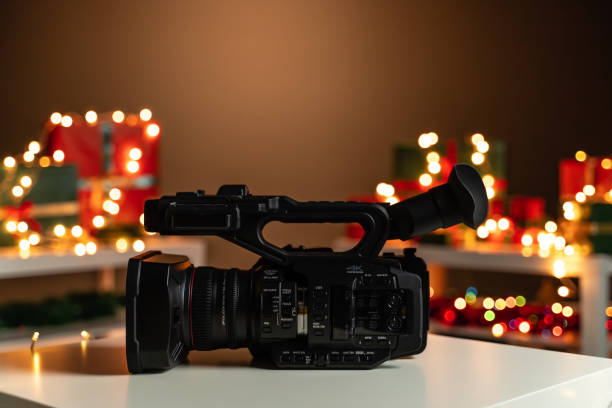 istock Home video camera side view, Christmas lights  and presents in background 1188388917