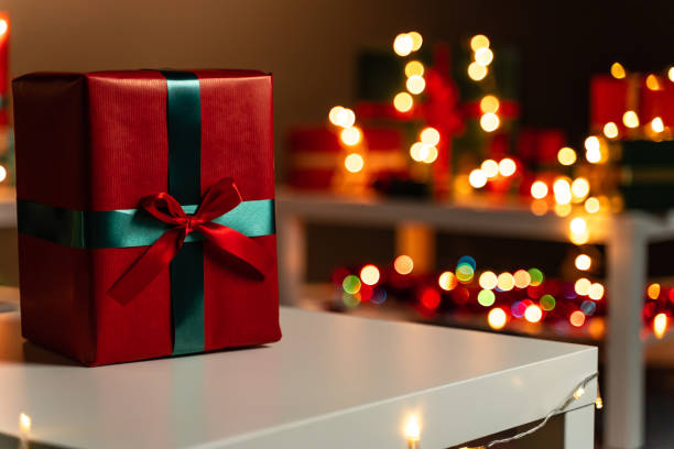 istock Red Christmas present on white table in front defocused Christmas lights in background, bokeh 1188389109