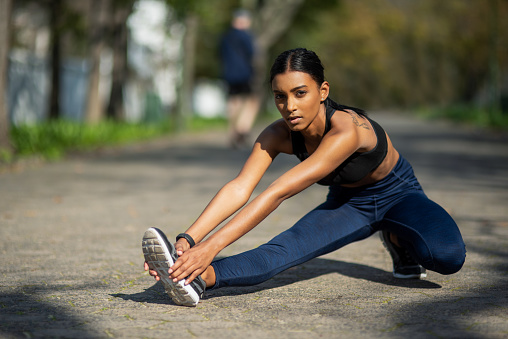 Portrait of a sporty young woman stretching her legs while exercising outdoors