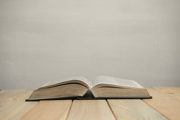 istock Open  Bible on a old wooden table and white wall background. Religion concept. 1188393717