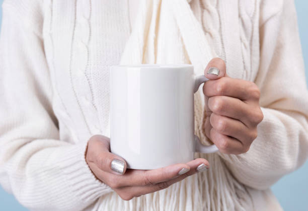 istock women hand holding white ceramic coffee cup. mockup for creative advertising text message or promotional content. 1188395136