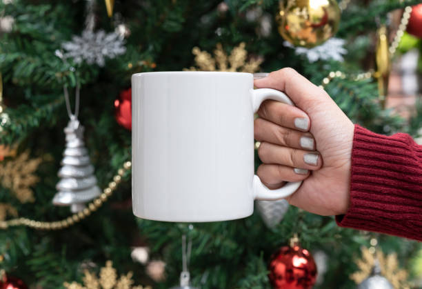 istock women hand holding white ceramic coffee cup on christmas tree background. mockup for creative advertising text message or promotional content. 1188395137