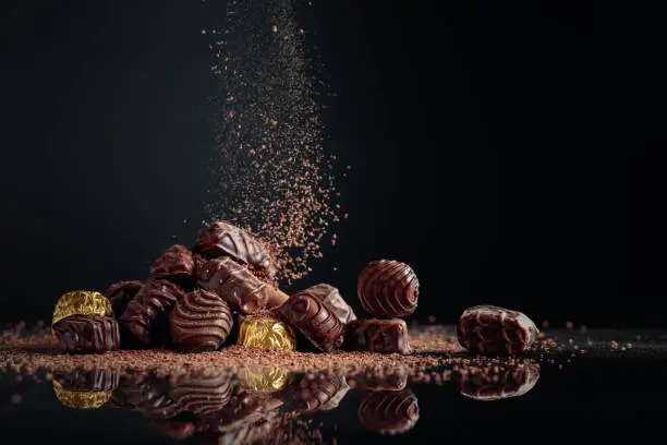 Chocolate candies on a black background sprinkled with chocolate chips. Copy space.