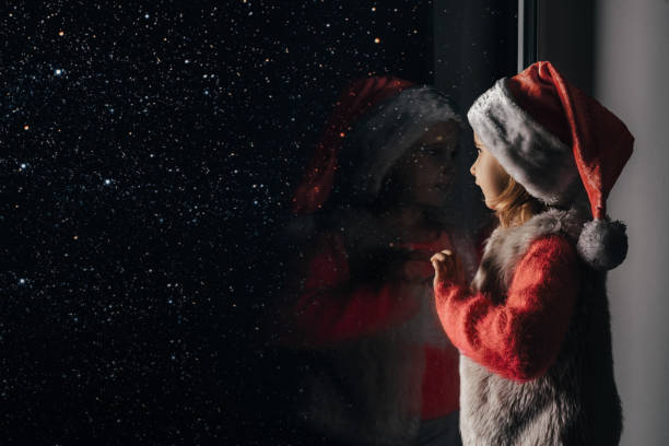 child looks out the window on christmas of Jesus Christ. stock photo