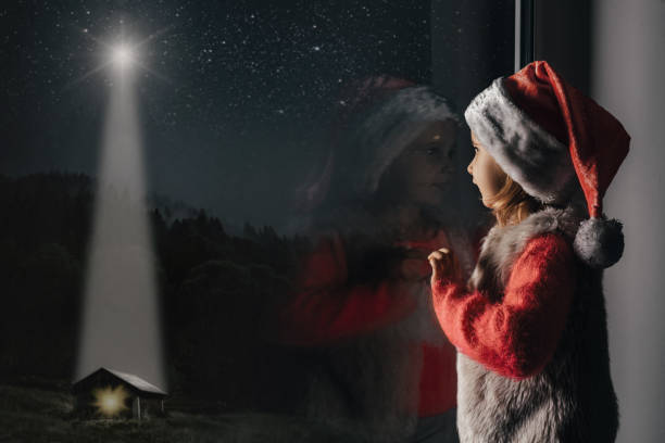 child looks out the window on christmas of Jesus Christ. stock photo