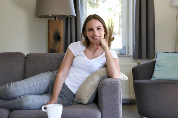 istock Young woman with white shirt on grey sofa 1188398355