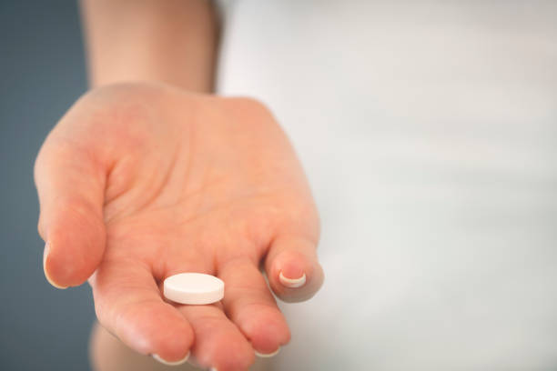 istock Woman hand holding a white pill. 1188401911