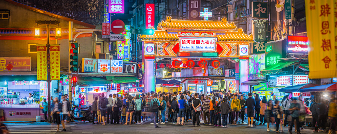 Crowds of shoppers and tourists at the neon lit entrance to Raohe Street Night Market in central Taipei, Taiwan’s vibrant capital city.