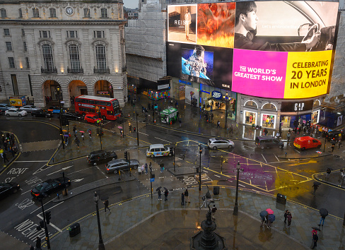 At night in London, in the foreground the sign for a subway sign and in the background traffic and a red double decker bus. The photo is taken in Piccadilly circus.