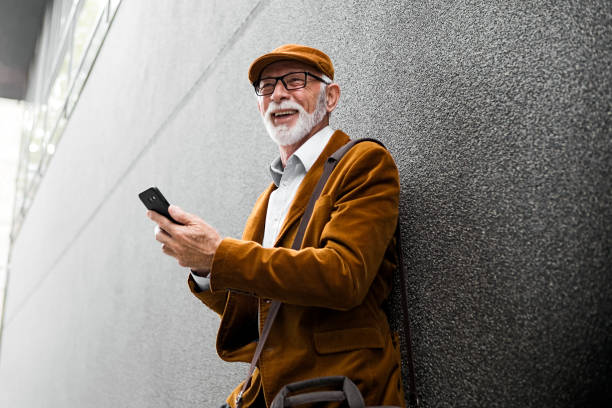 istock Fashionable Senior Man Outdoors sanding massage leaning on a office building wall 1188409788